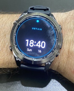 ObtAIn Smart Watch with black face and cyan OBTAIN display